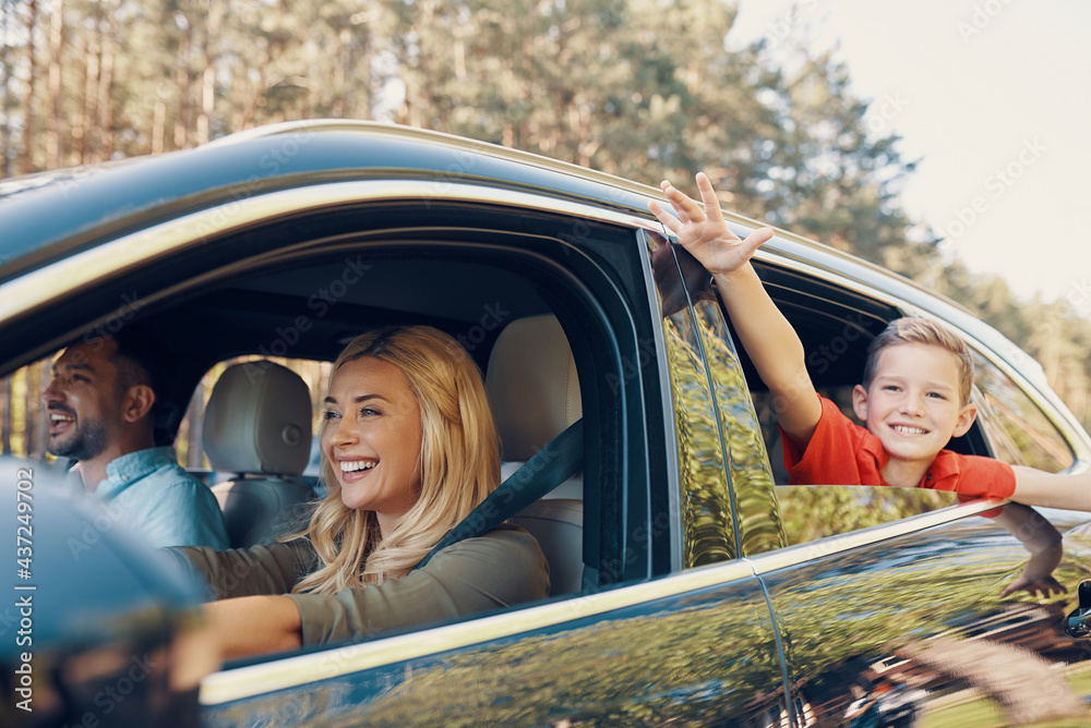 Young beautiful family with little boy having fun and smiling while driving in the car