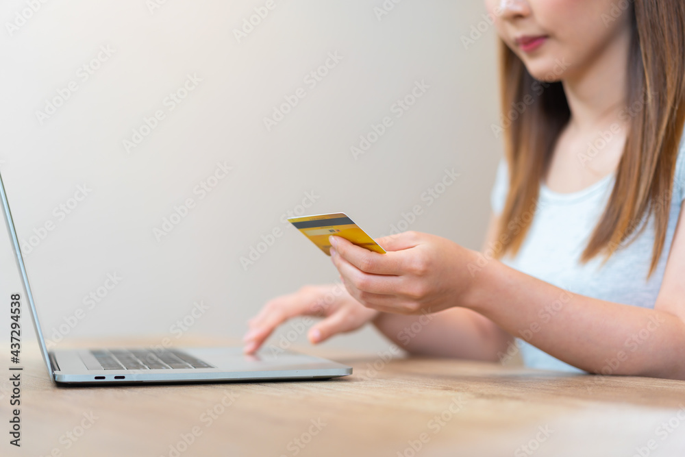 亚洲女子拿着信用卡在键盘上打字进行网上购物或网上银行业务