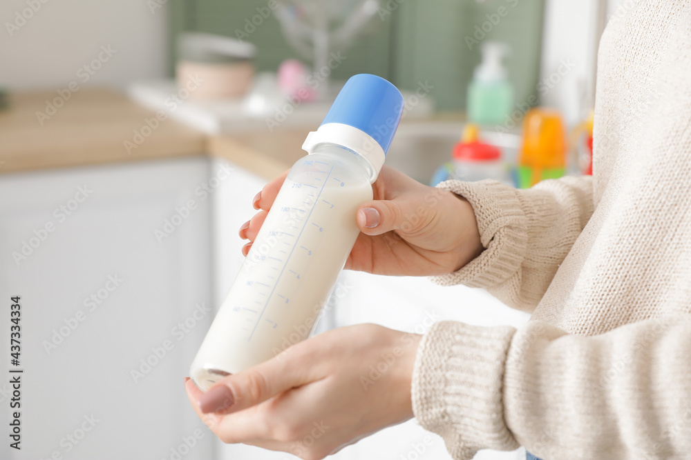 厨房里拿着婴儿奶瓶的女人，特写