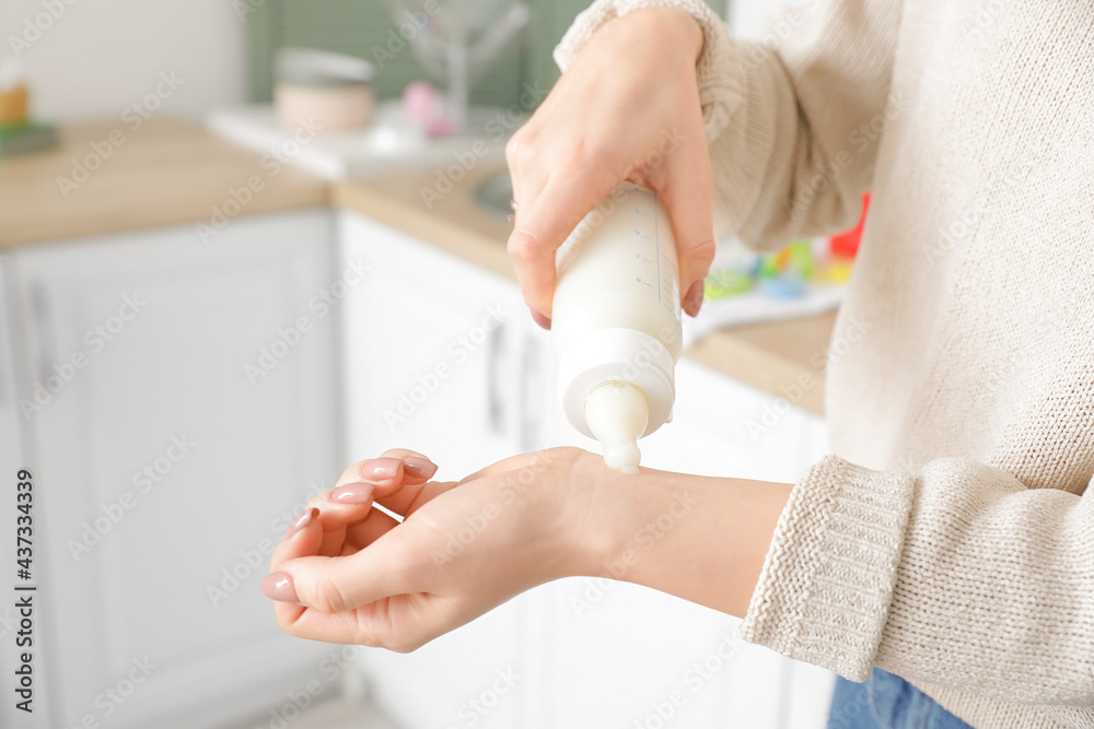 妇女在厨房检查婴儿配方奶粉的温度，特写