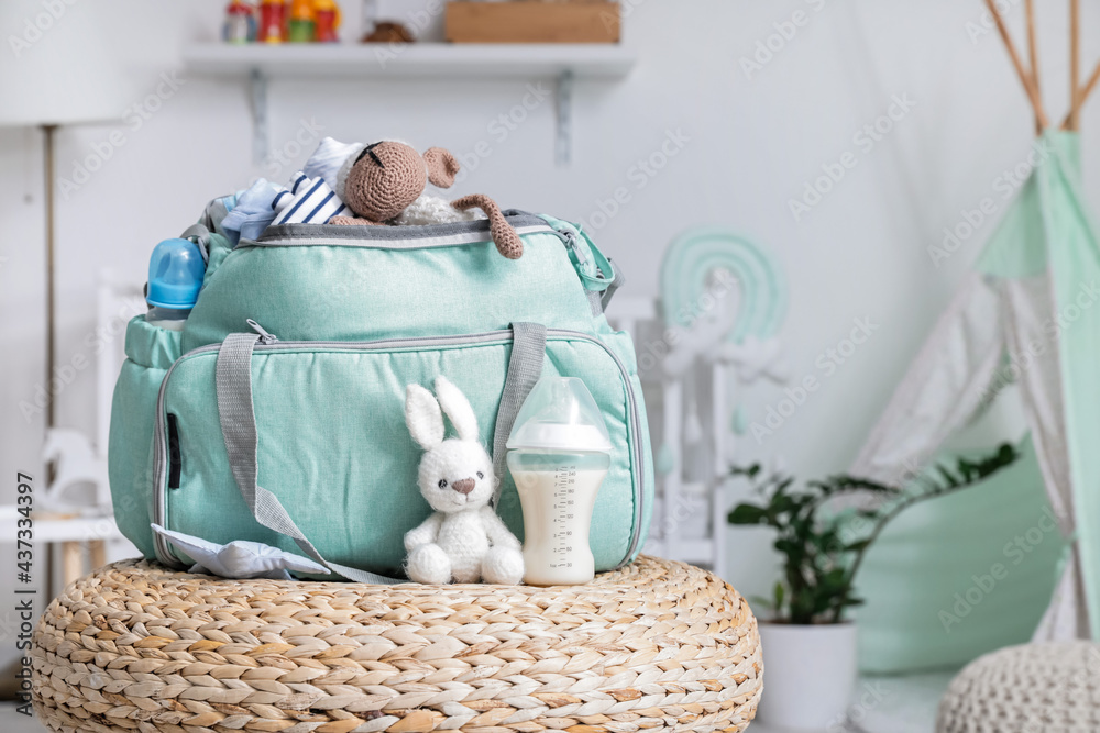 婴儿奶瓶和家里脚凳上的玩具袋
