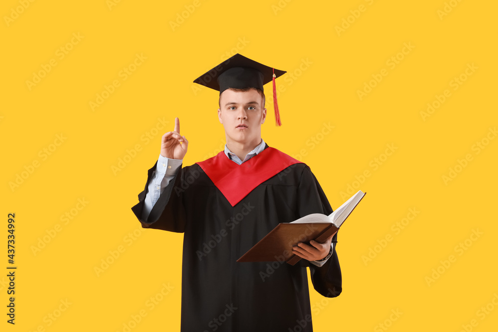 男毕业生，食指在彩色背景上抬起