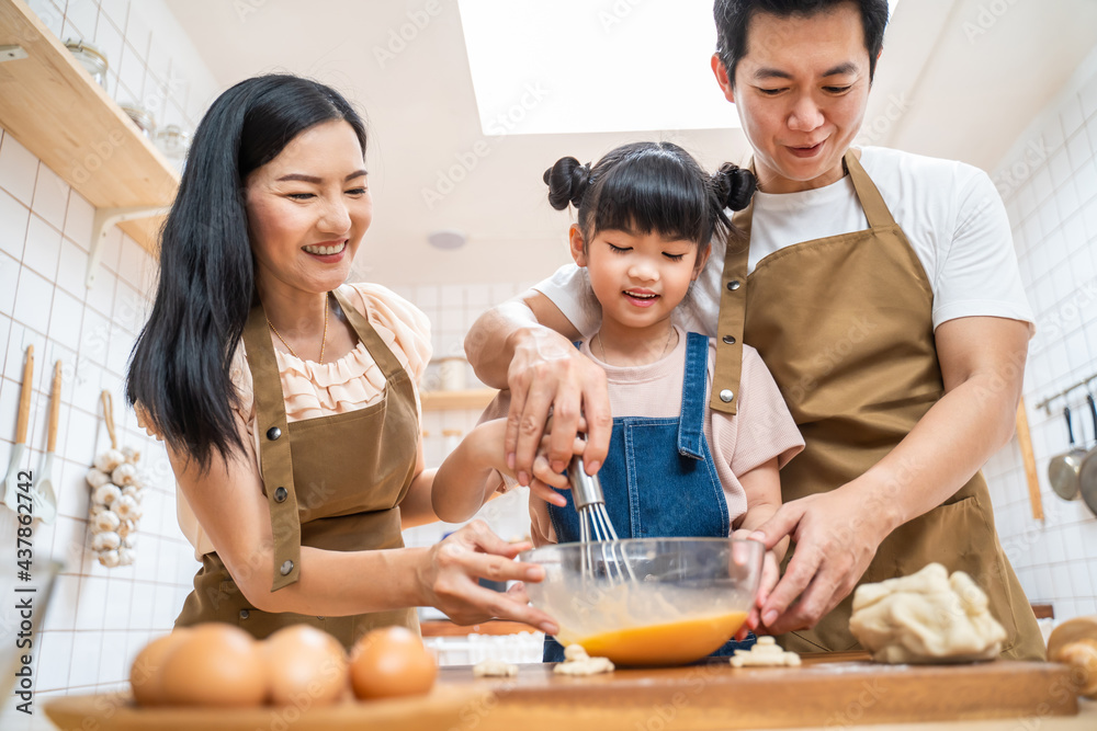 厨房里的幸福家庭父母教孩子在家里烤面包和食物