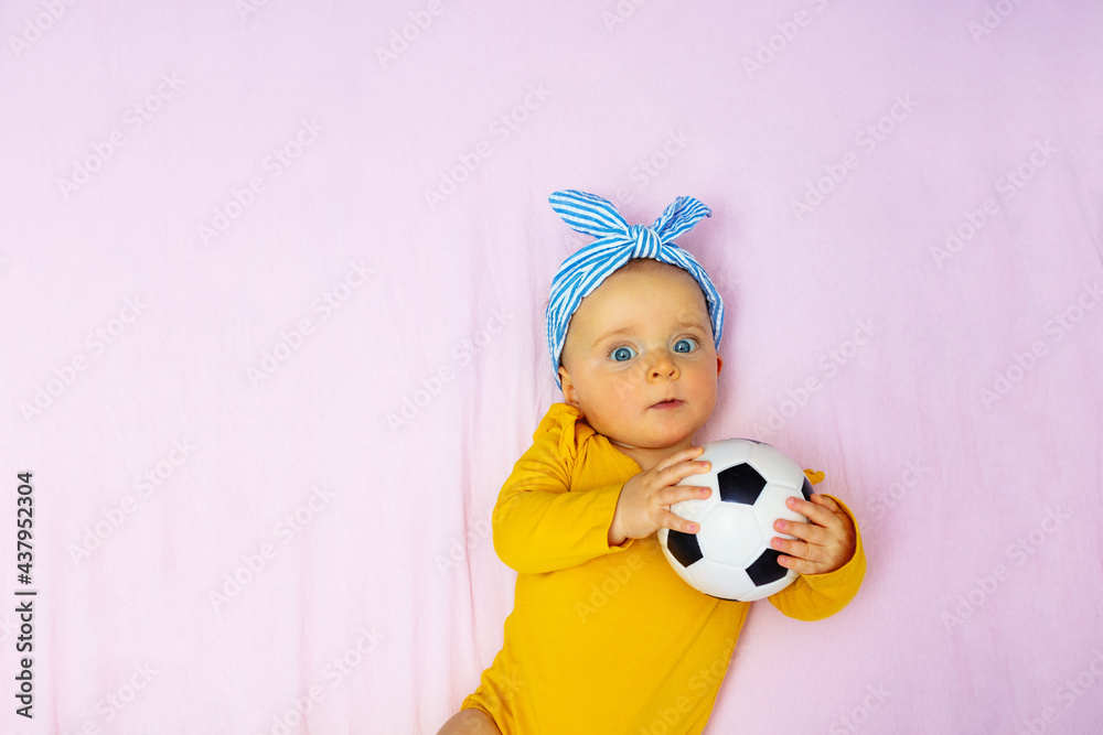 Little girl wear blue bow play with soccer ball