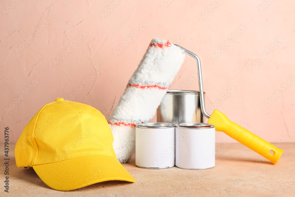 Cap with roller and cans with paint on color background