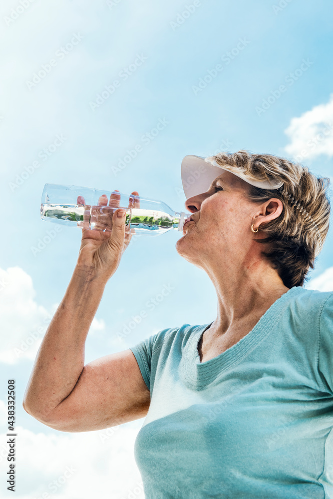 Senior woman drinking water after an exercise