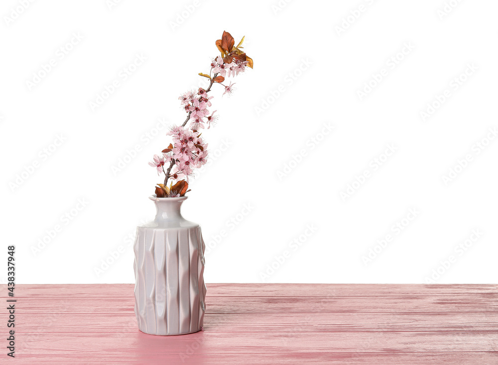 白色背景下，木桌上有美丽的开花树枝的花瓶