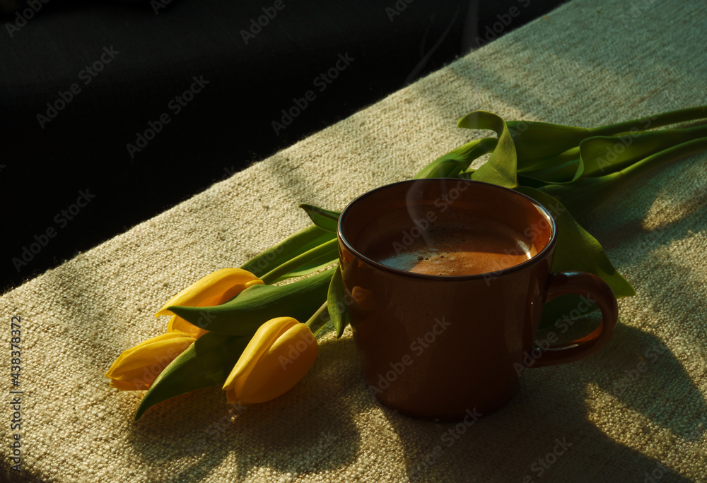 `A mug of hot coffee with steam above the cup under morning sunlight. Relaxing morning with beautifu