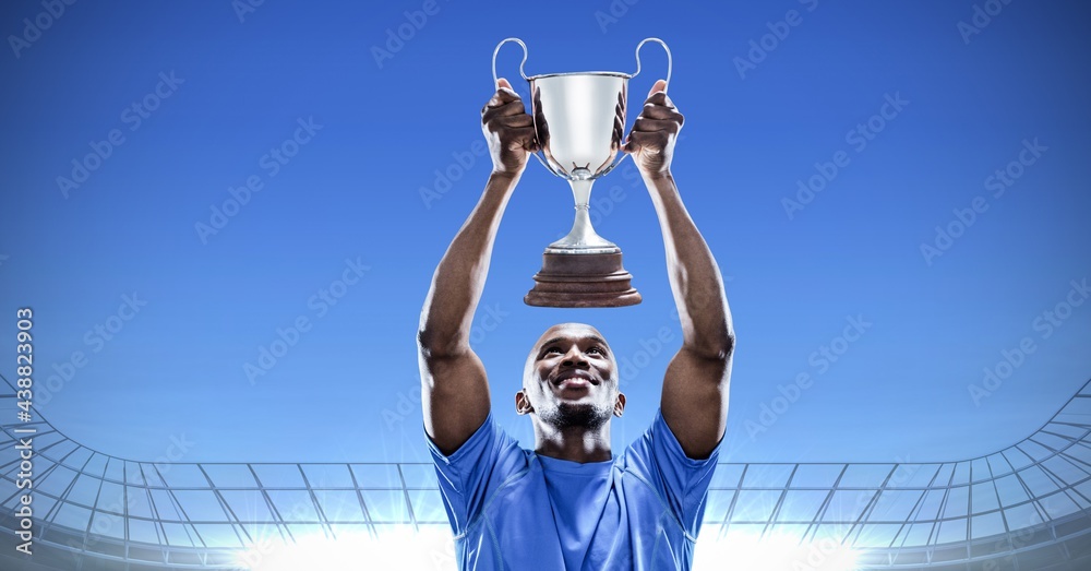 Composition of sportsman celebrating victory, holding trophy at stadium