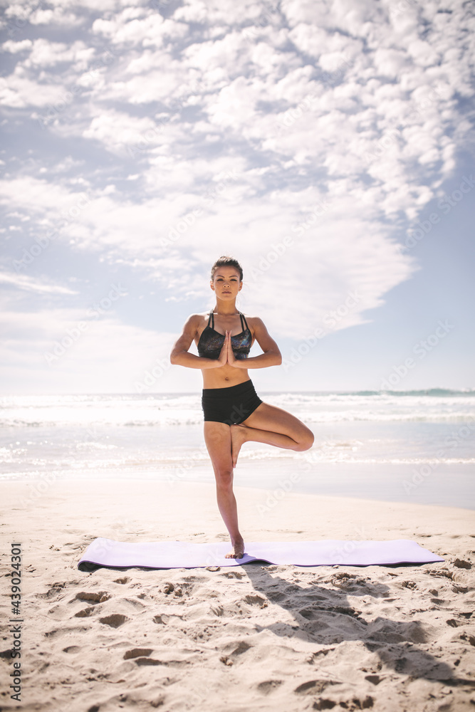 Fitness woman at beach meditating in tree pose yoga