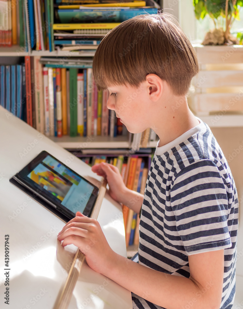 一个穿着水手背心的八岁高加索男孩使用平板电脑。特写。