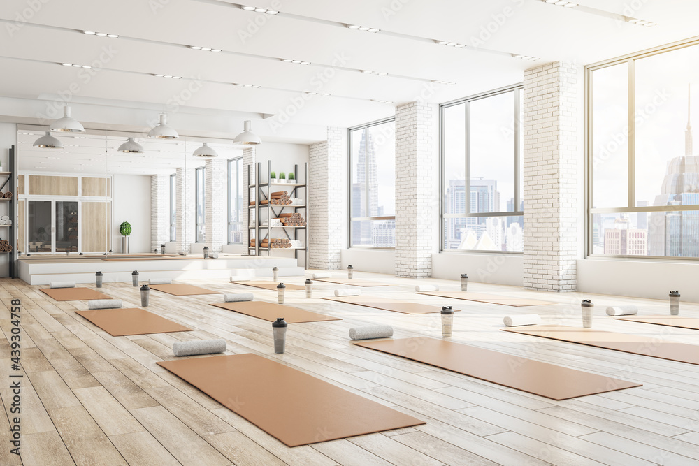 Concrete yoga gym interior with equipment, daylight and wooden flooring. Healthy lifestyle concept. 