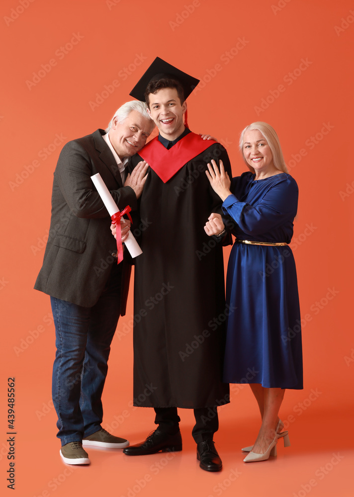 快乐的男毕业学生和他的父母在彩色背景下