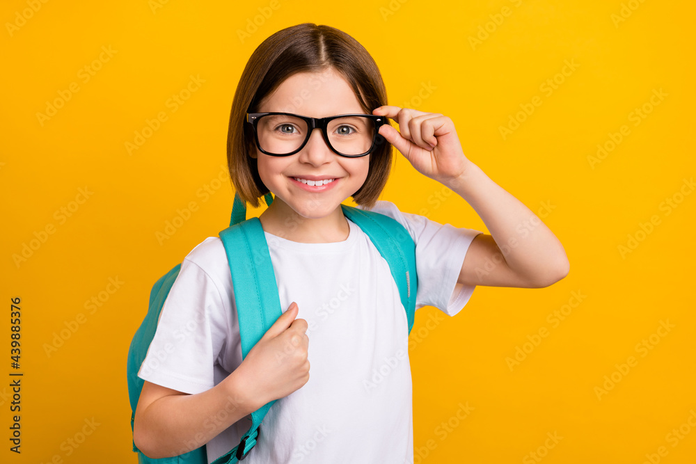Photo portrait small schoolgirl smiling wearing spectacles blue rucksack isolated vibrant yellow col