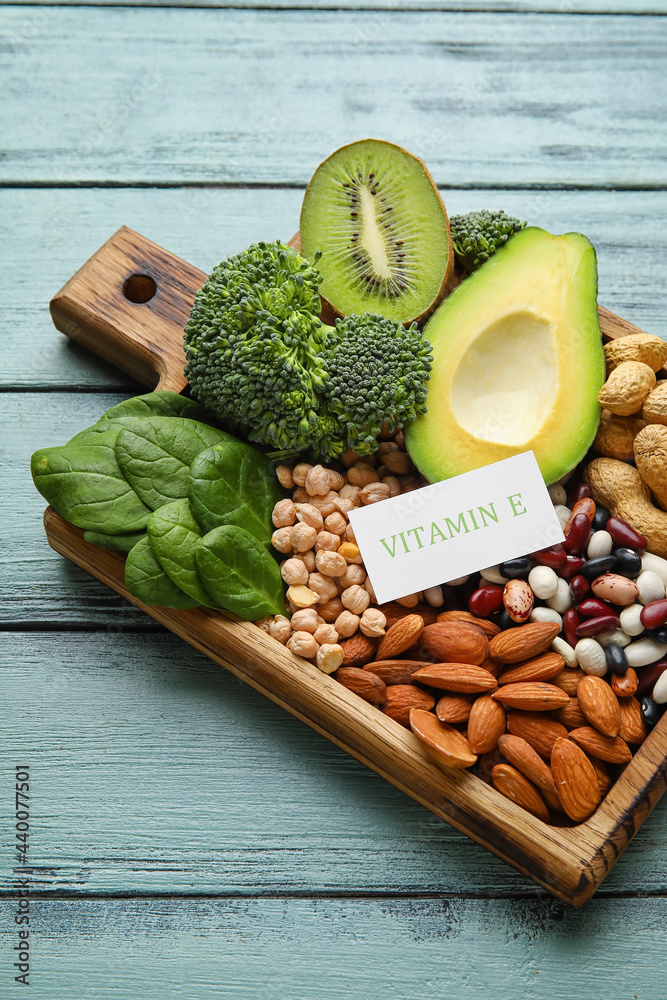 Board with healthy products rich in vitamin E on color wooden background, closeup