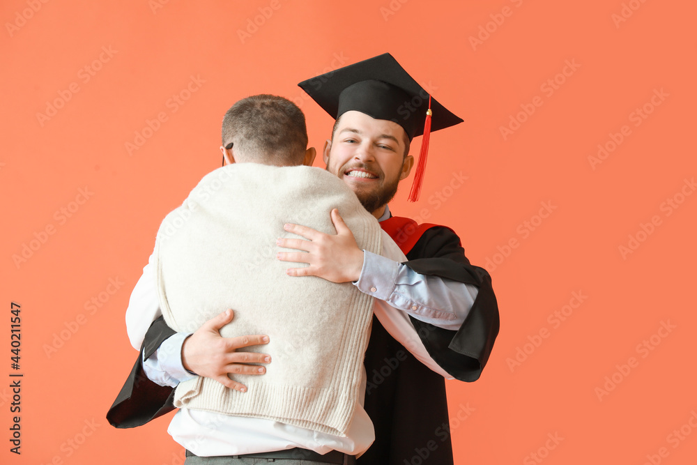快乐的男毕业学生和他的父亲在彩色背景下