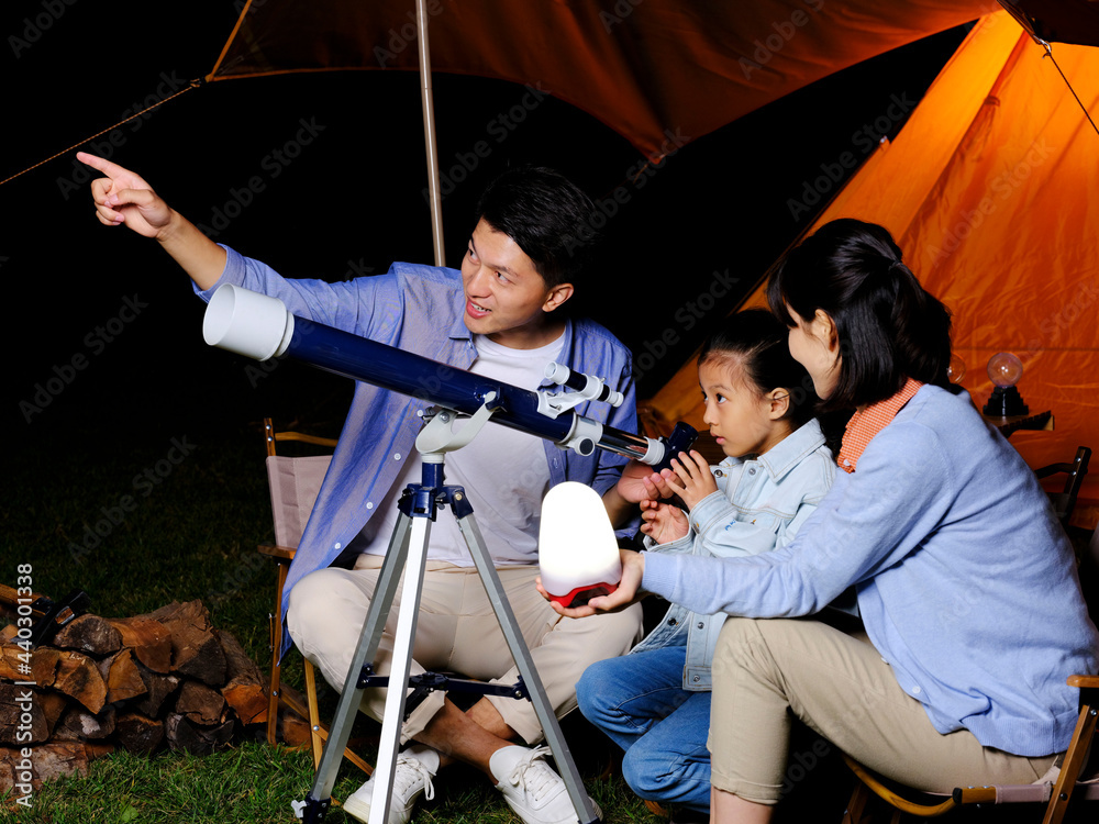 一个幸福的三口之家在户外使用望远镜
