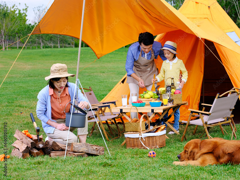 Happy family of three and pet dog cooking outdoors