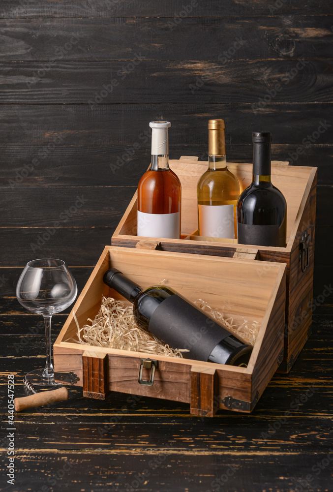 深色木质背景的装有葡萄酒和玻璃杯的盒子