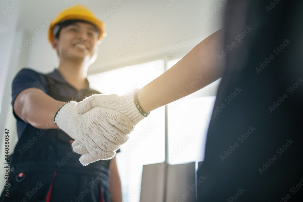 Asian Craftsman wear yellow helmet, handshake with construction worker
