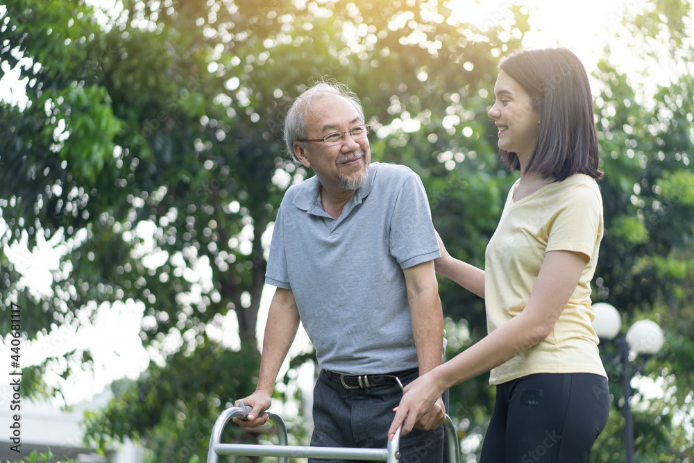 亚洲小女儿帮助残疾的高祖父在花园里散步。