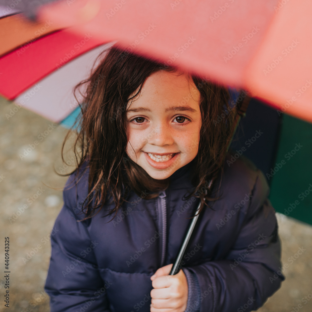一个小女孩在户外家庭旅行时撑着伞微笑