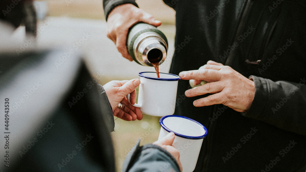 Senior man pouring morning coffee from a thermal bottle