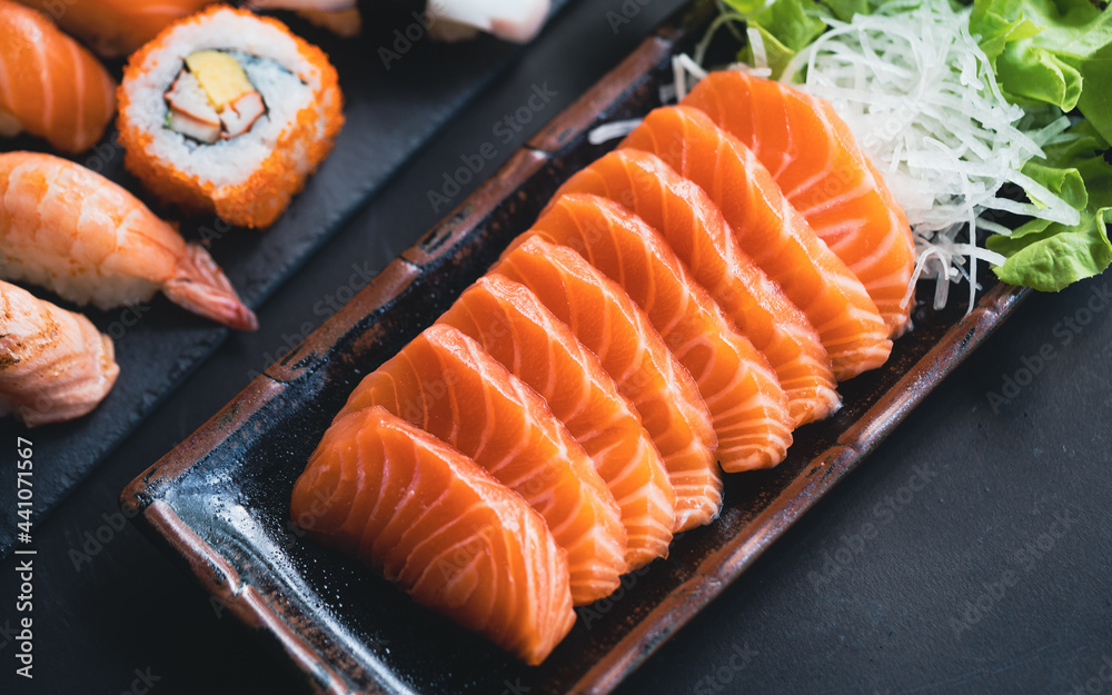 日本自助餐厅菜单上的三文鱼刺身。黑盘子三文鱼片上的新鲜三文鱼柳。A