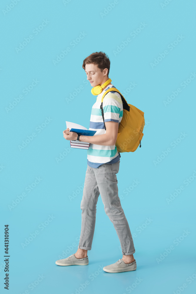 Male student with books on color background