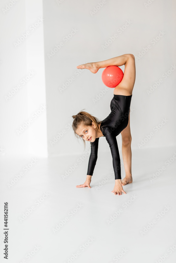 小女孩在白房持球练习艺术体操。儿童体操和训练