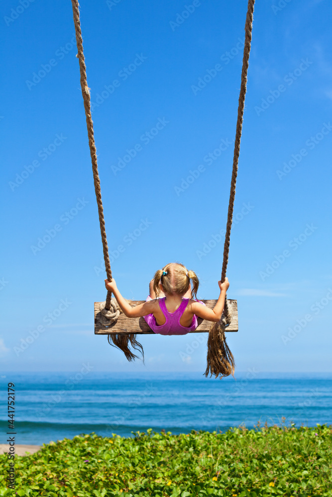 快乐的女孩在半空中荡秋千玩得很开心。在海边的绳索秋千上倒立飞行。Trav