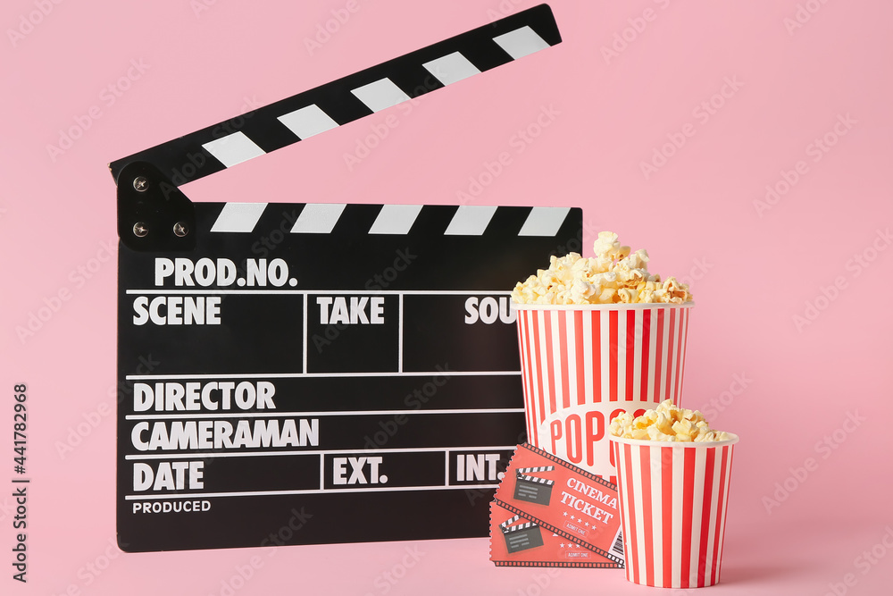 Popcorn with tickets and movie clapper on color background