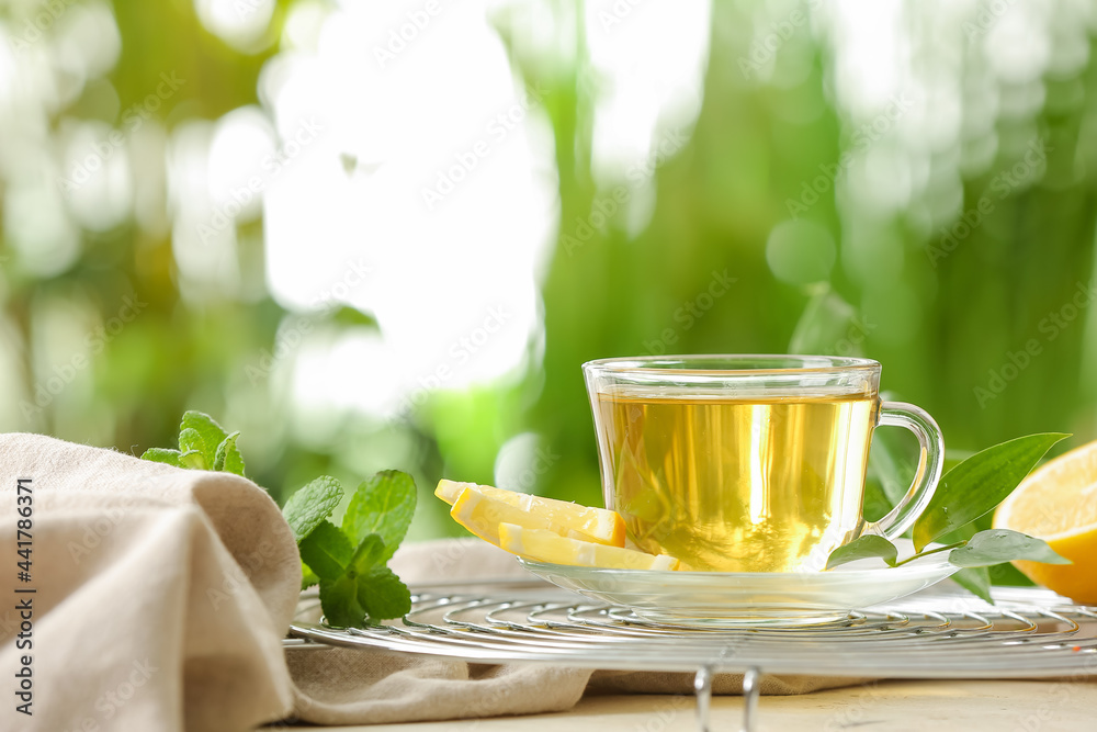 Grid with cup of tasty green tea and ingredients on table outdoors
