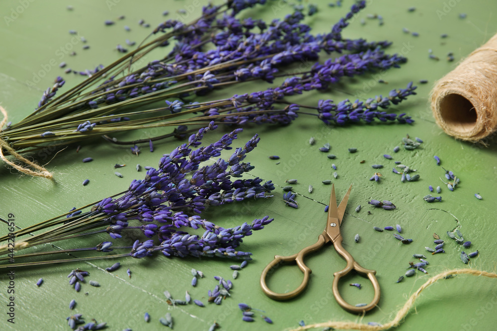 美丽的淡紫色花朵，剪刀和绳子在彩色木背景上，特写