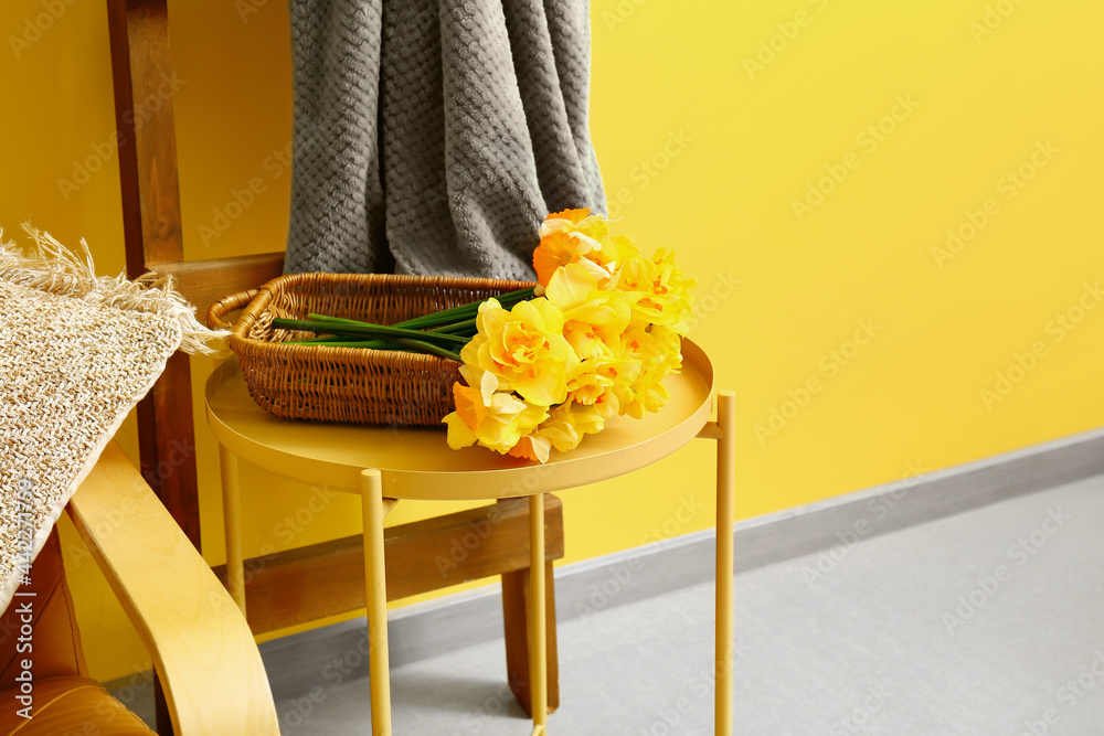 Table with beautiful narcissus flowers in room