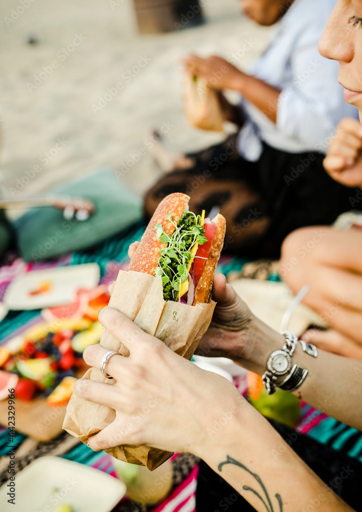 在海滩上吃三明治的女人