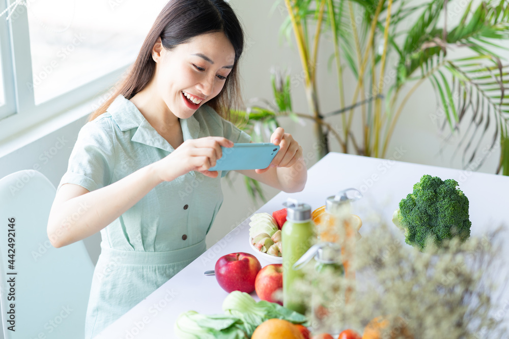一名亚洲妇女用手机为她的植物餐拍照