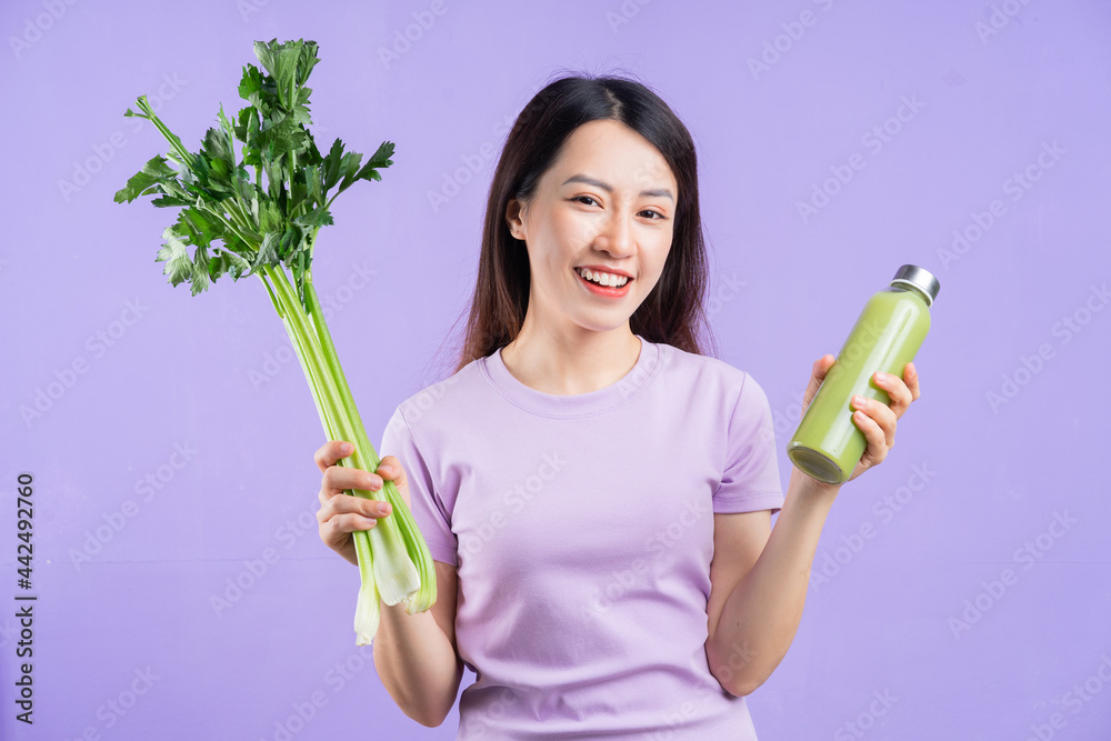 年轻的亚洲女人拿着一瓶紫底果汁