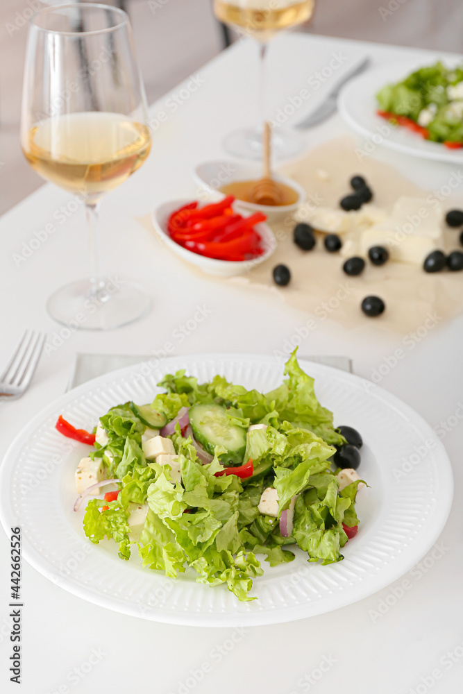 餐厅餐桌上摆着新鲜的希腊沙拉和几杯葡萄酒
