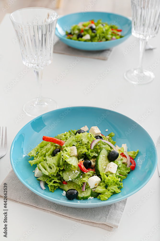 餐厅餐桌上有新鲜希腊沙拉和玻璃杯的盘子