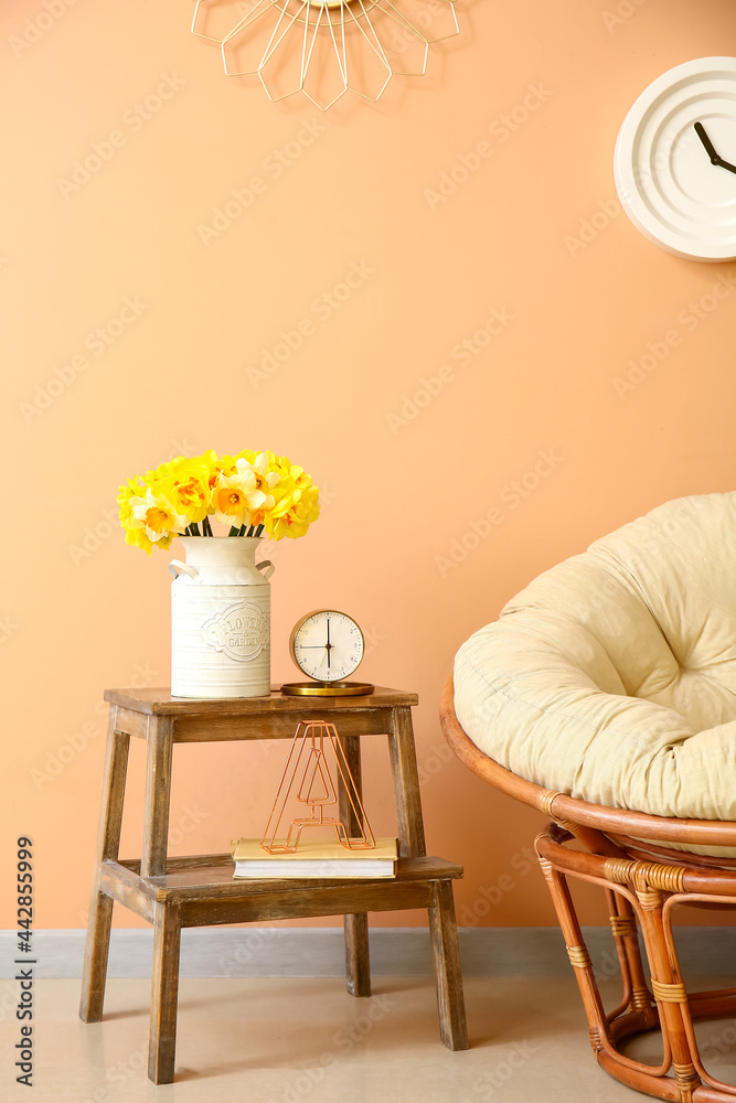 阶梯上有漂亮的水仙花的花瓶，靠近彩色墙的扶手椅