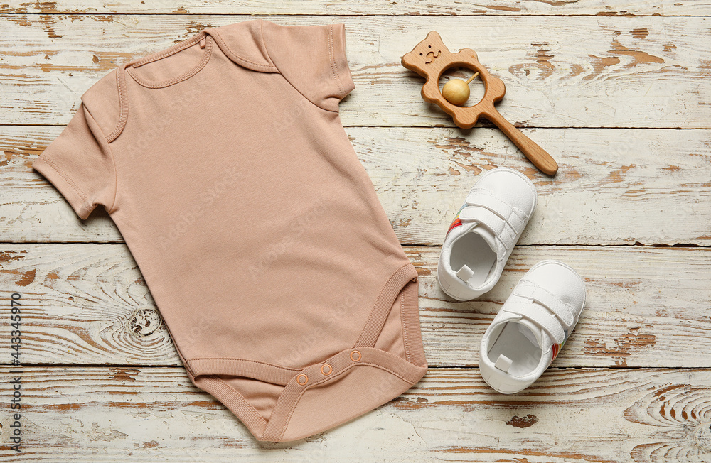 浅色木质背景下的婴儿衣服、鞋子和玩具