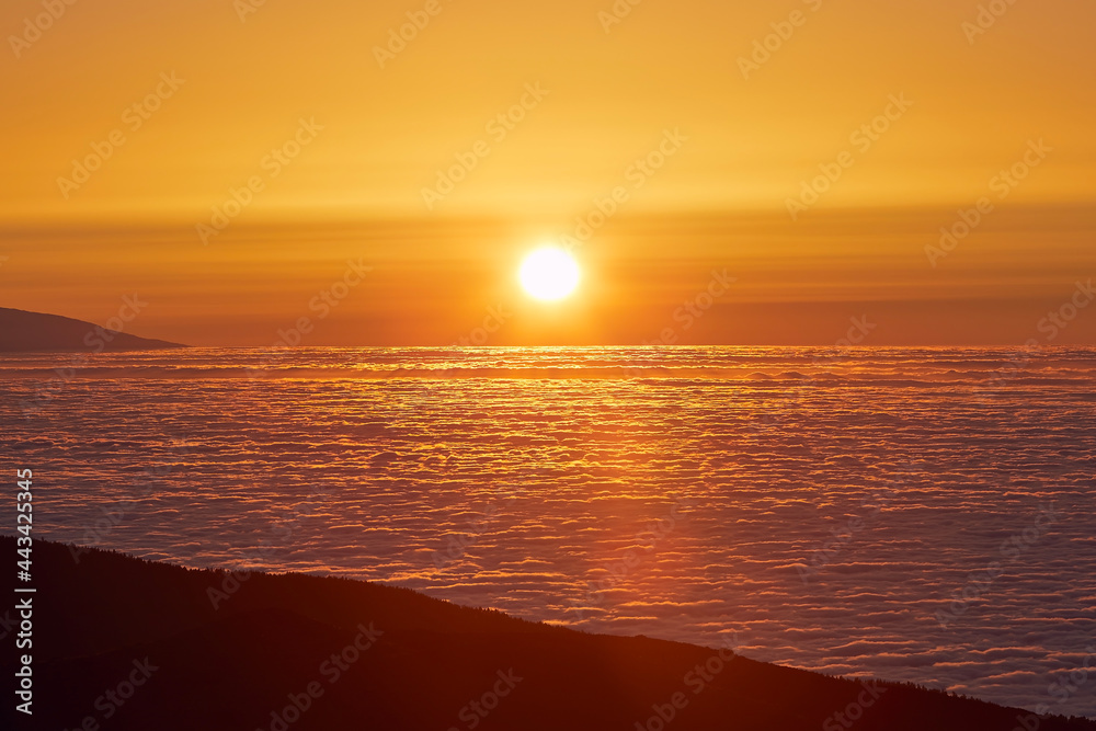 云层之上的太阳。金色日落下的山脉景观。西班牙加那利群岛特内里费岛。