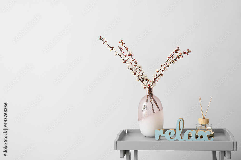 在浅色背景下，桌上摆放着盛开的春枝花瓶