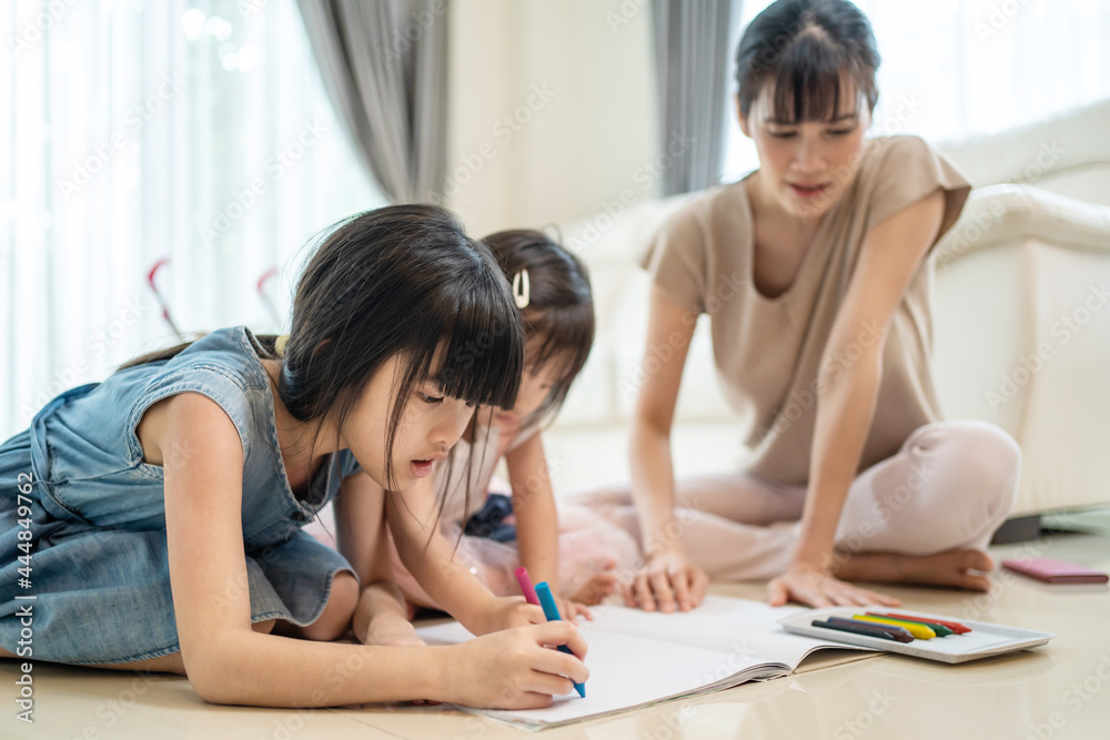 Asian Little siblings girl draw and color picture with mother on floor