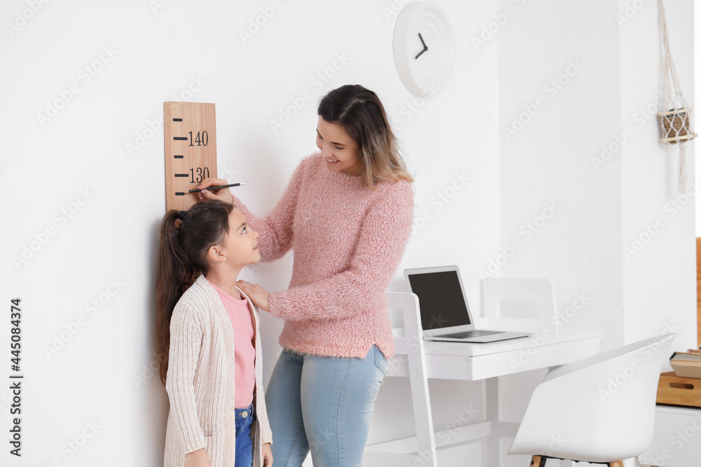 妇女在家测量小女儿的身高