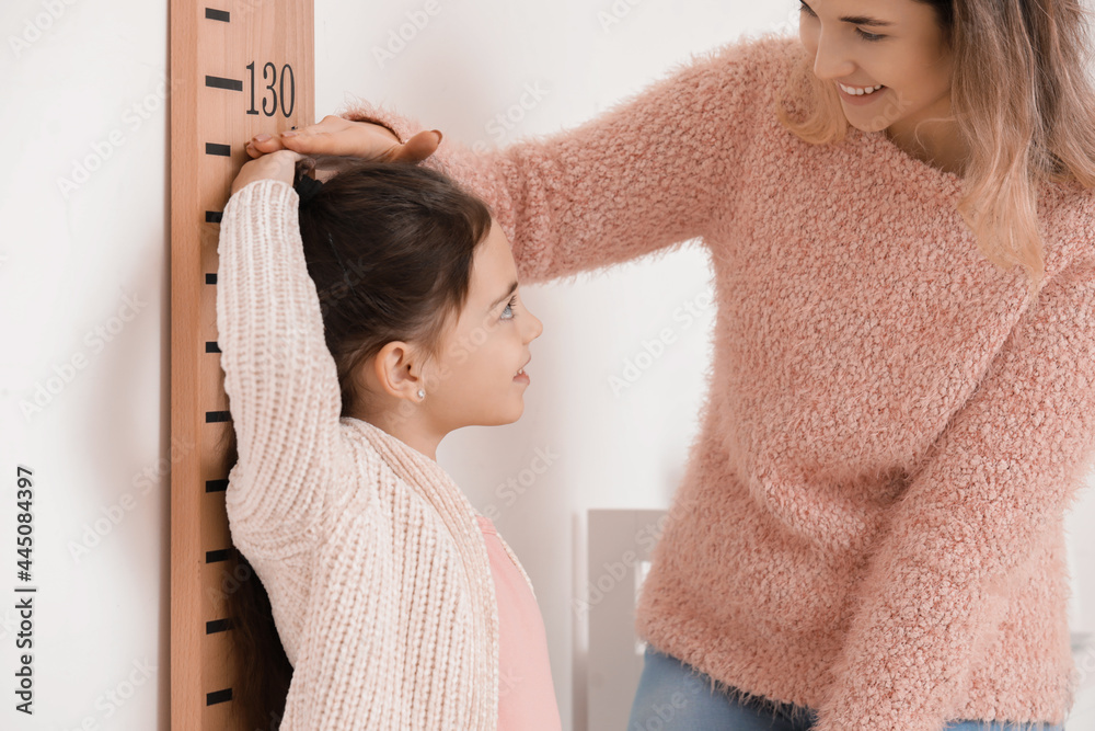 女人在家给小女儿测量身高