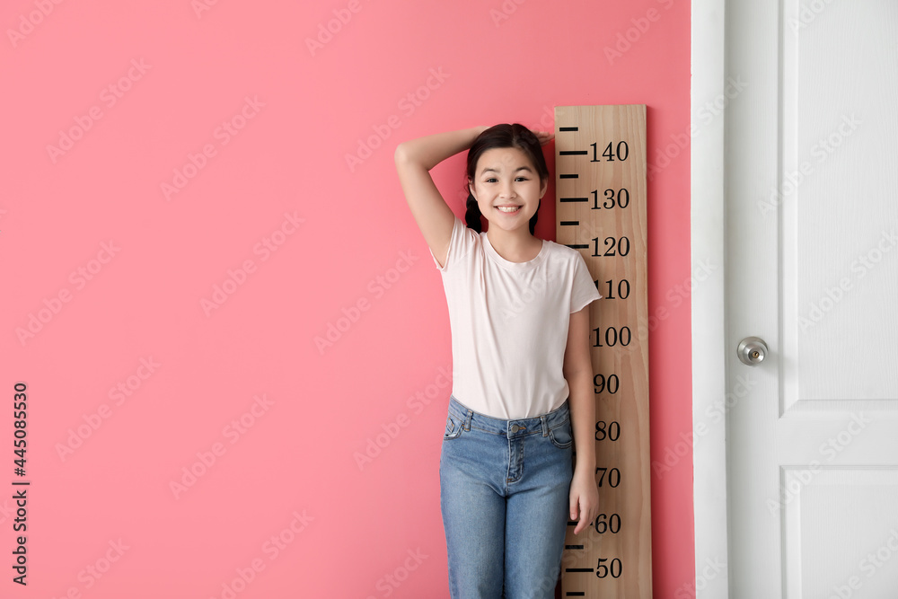 小女孩在彩色墙附近测量身高