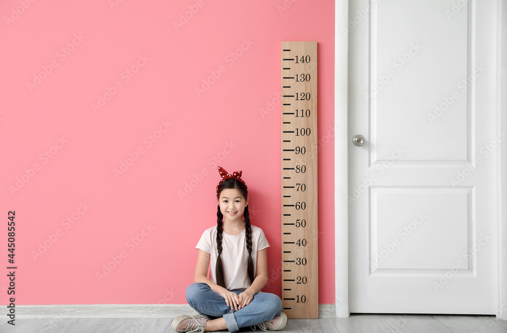 小女孩在彩色墙附近测量身高