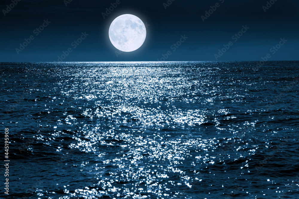 这轮蓝色的满月在平静的海洋上明亮地升起，在海浪中闪闪发光